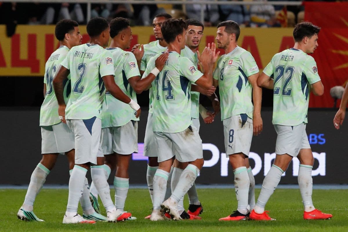 Futbollistë të Zvicrës me fanella të çelëta përshëndesin njëri-tjetrin në fushë.