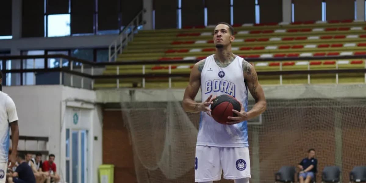 Basketbollist me fanellën e bardhë të Borës mban topin në duar në një palestër sportive.
