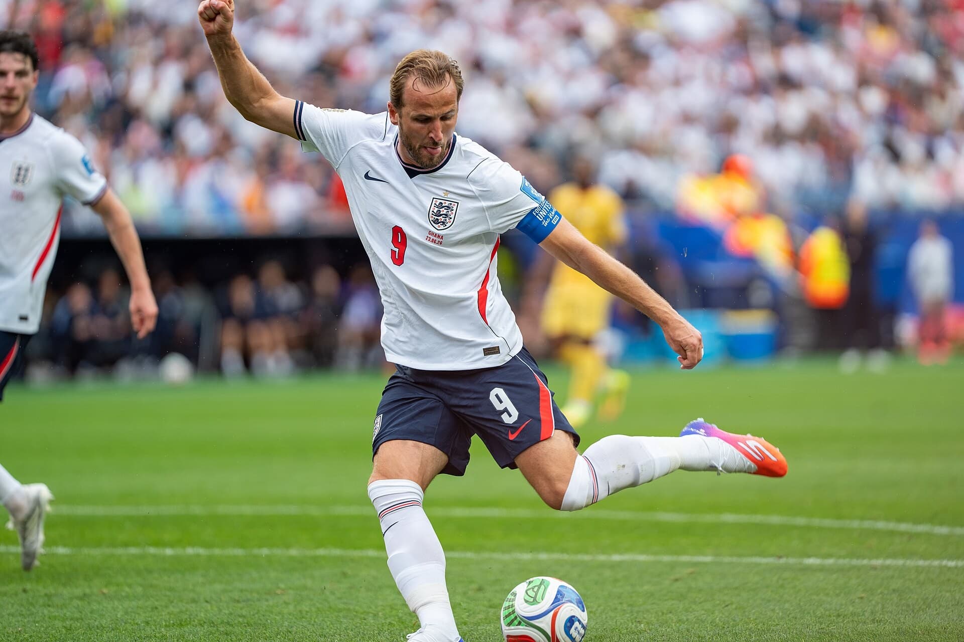 Harry Kane me fanellën e Anglisë duke goditur topin në fushë.