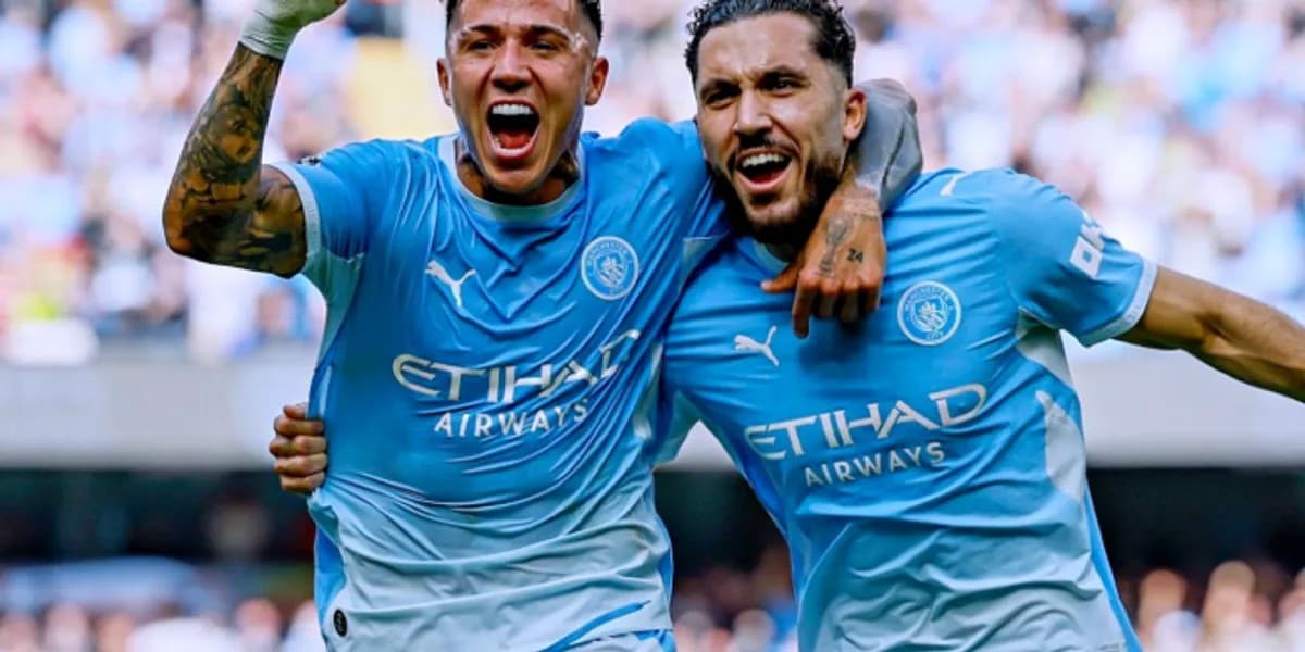 Dy futbollistë me fanellat e kaltra të Manchester Cityt, me krahët rreth njëri-tjetrit në stadium.