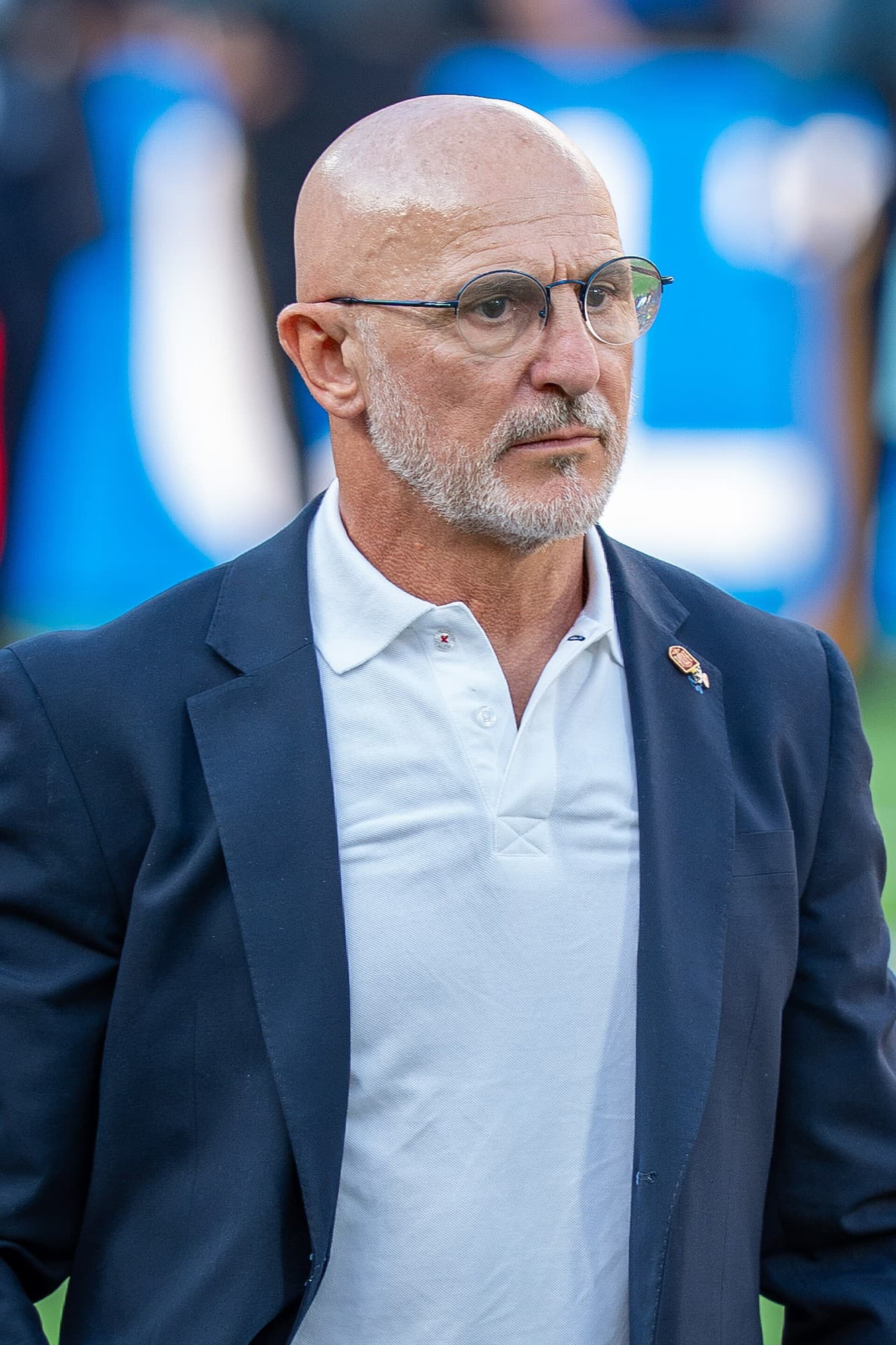 Luis de la Fuente me syze, xhaketë blu të errët dhe bluzë të bardhë në fushën sportive.