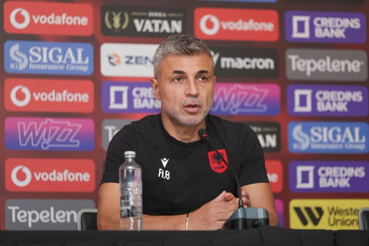 Alban Bushi ulur para mikrofonit në një konferencë për media, me sfond sponsorësh.